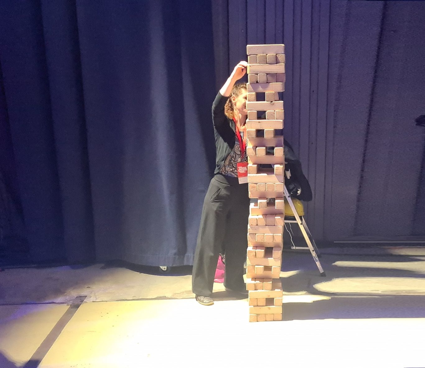 XXL - Wackelturm Ein Kind zieht einen Block aus einem hohen Holzspielturm.