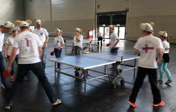 Tischtennisplatte Gruppenspieler in T-Shirts spielen Tischtennis in einer großen Halle.