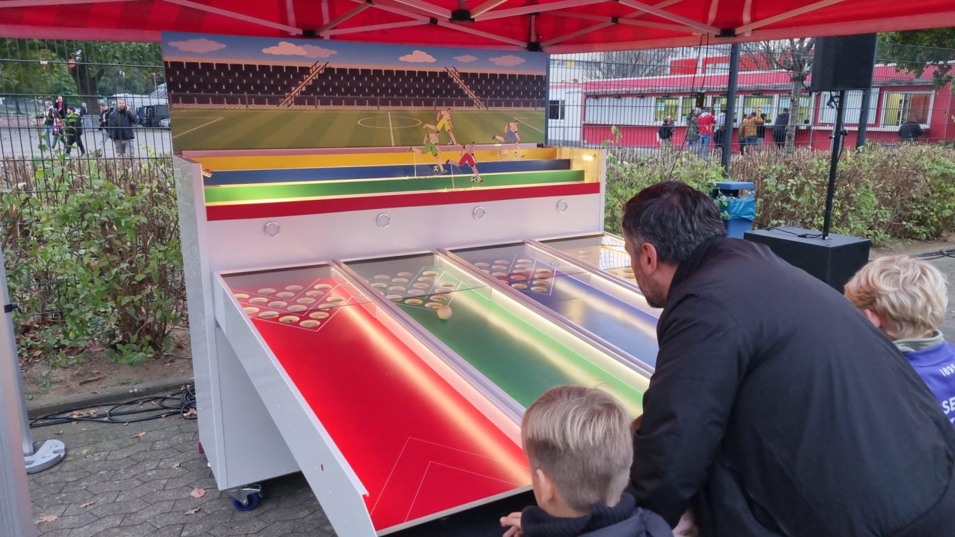 Renn-Derby mit versch. Motiven Personen spielen an einem bunten Wettlaufspiel unter einem Zelt.