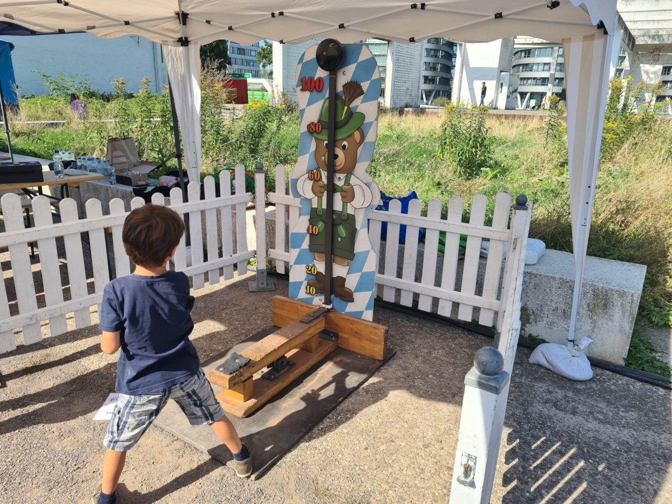 Hau den Lukas Kids Ein Kind spielt an einem bunten Holzspielgerät unter einem Zeltdach.